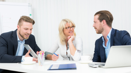 drei Personen sitzen in einem Büro und arbeiten zusammen